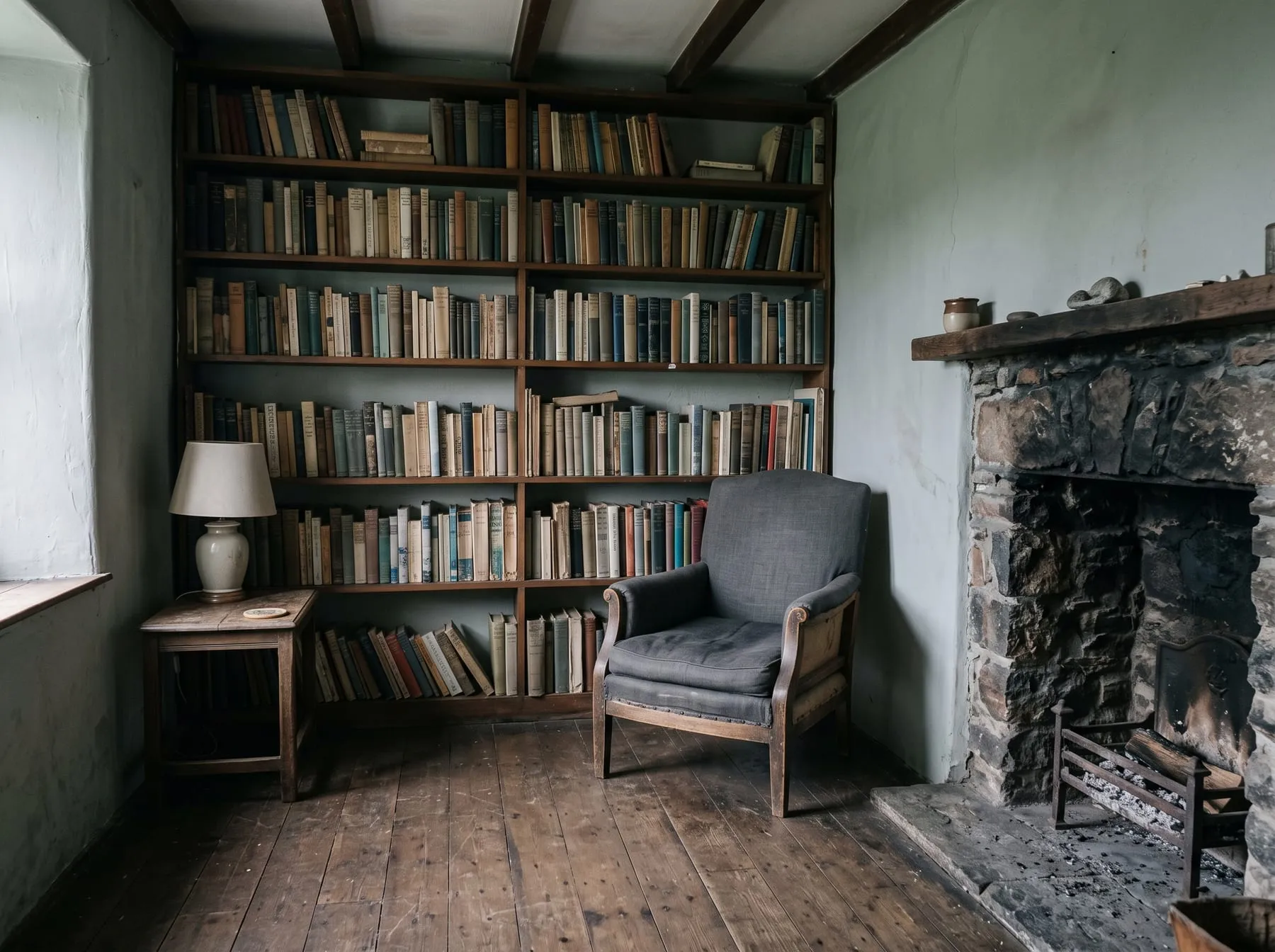 The reading room: a wall of books, one armchair and a cold fireplace