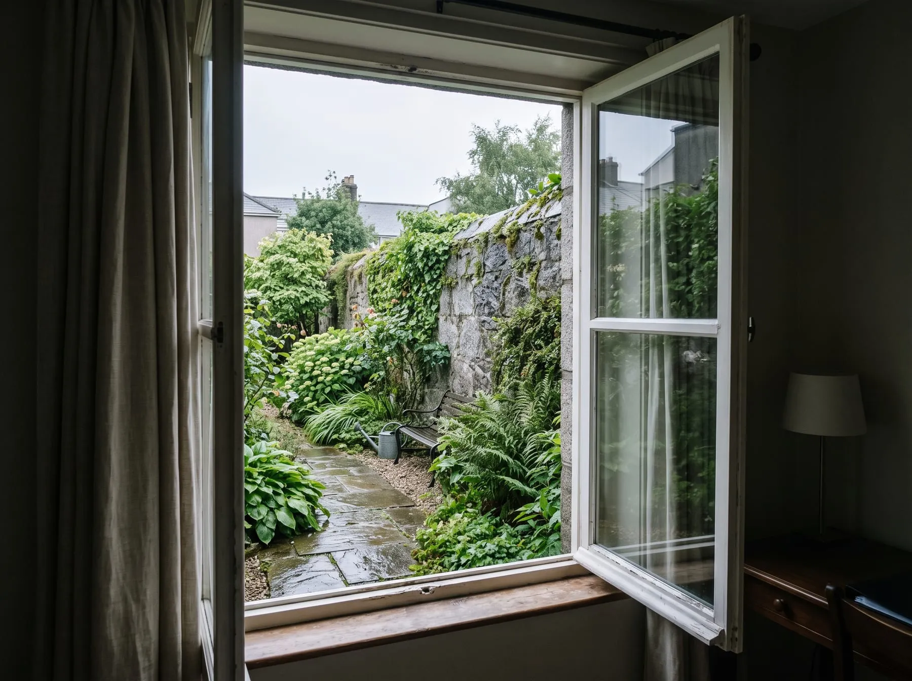 The open window of the room, looking onto the walled garden and its stone wall